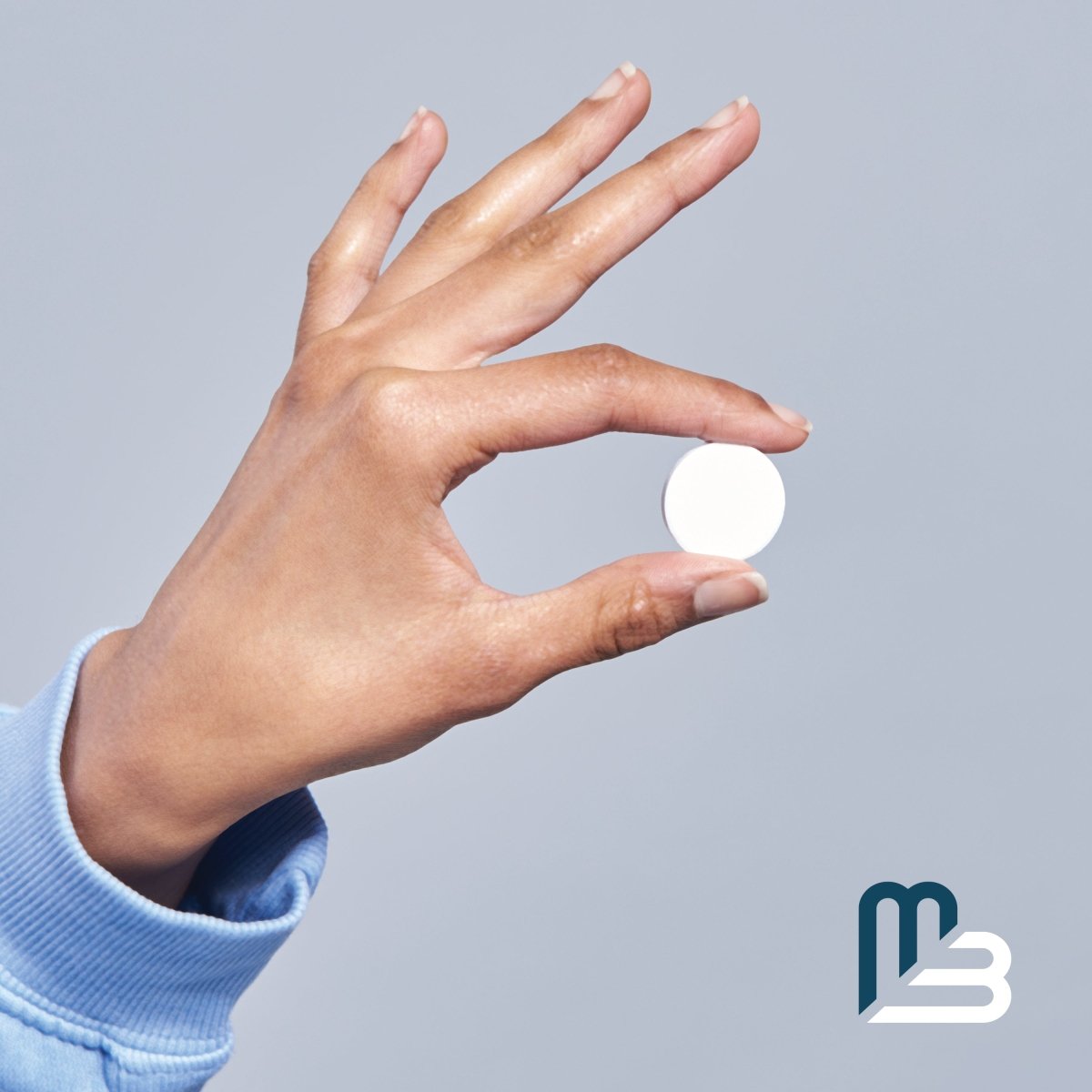 Hand holding a white tablet against a gray background