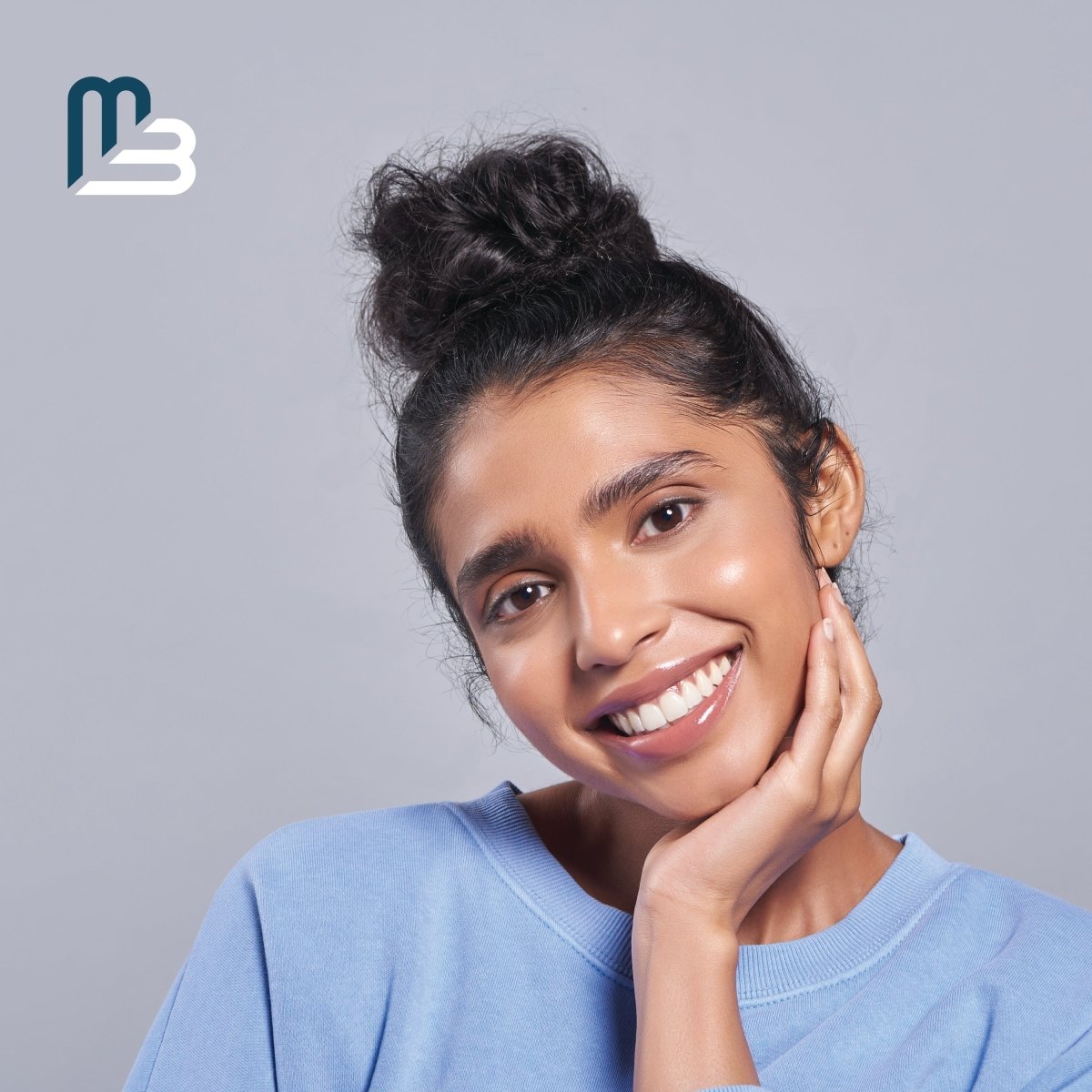 Woman with a smile on a gray background with a visible M3 logo.