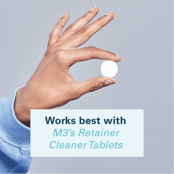 Hand holding a tablet suggesting using the denture bath with M3 retainer cleaner tablets. 